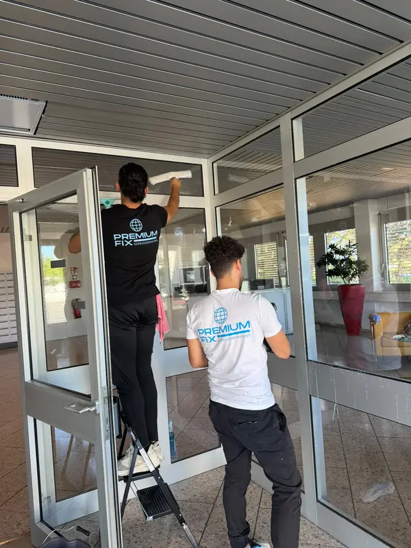 PremiumFix Mitarbeiter reinigt die Glasfassade eines Bürogebäudes von der Leiter aus